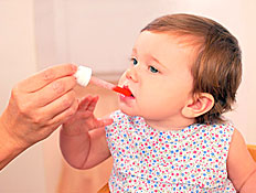 תינוקת יפה מקבלת תרופה אדומה מהיד של אמא שלה (צילום: jupiter images)