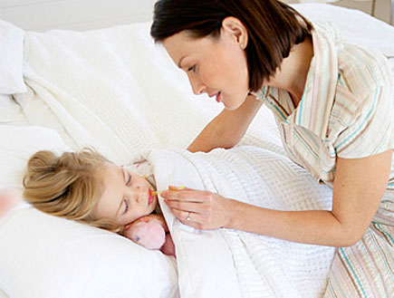 אמא מודדת חום לבת שלה שישנה במיטה