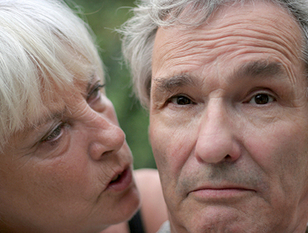 אישה מבוגרת מדברת לאוזנו של איש מבוגר (צילום: Joris van Caspel, Istock)