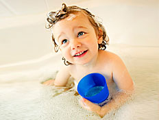 ילד קטן מביט למעלה באמבטיה עם כוס כחולה ביד (צילום: jupiter images)