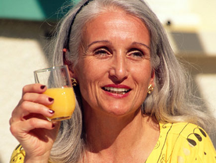 אישה מבוגרת עם שיער אפור שותה מיץ לבושה צהוב (צילום: jupiter images)