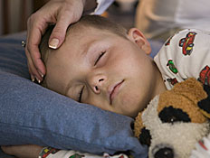 ילד ישן במיטה והיד של אימו מלטפת את ראשו (צילום: jupiter images)