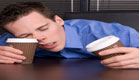 עייפות ותזונה-אדם נרדם על שולחן,מחזיק 2 כוסות קפה (צילום: Dizzy, Istock)