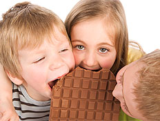 שלושה ילדים נוגסים בחפיסת שוקולד (צילום: jupiter images)