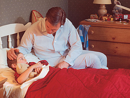אב מלטף את ראש בנו ששוכב לישון במיטה (צילום: Comstock, Istock)