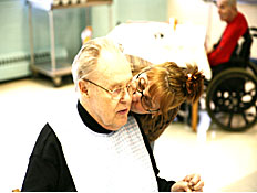 אישה עומדת ומנשקת לחי של קשיש שיושב (צילום: jupiter images)