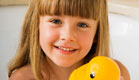 ילדה עם פוני באמבטית קצף מחזיקה ברווז צהוב ומחייכת (צילום: jupiter images)