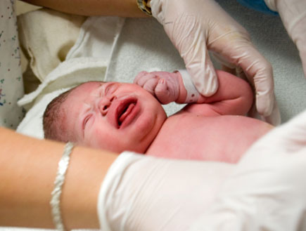 ידיים עם כפפות מטפלות בתינוק צורח (צילום: bmcent1, Istock)