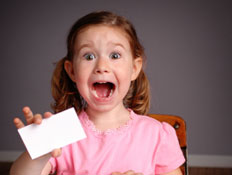 ילדה בורוד מחזיקה נייר לבן על שולחן עץ וצורחת מפחד