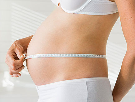 בחורה בהריון בחזייה ותחתונים לבנים מודדת בטן בסרט מדידה (צילום: jupiter images)