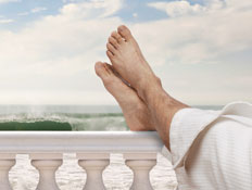 רגליים על מעקה מרפסת לבנה (צילום: Shutterstock)