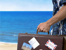 איש בחולצה פרחונית מחזיק מזוודה (צילום: istockphoto)