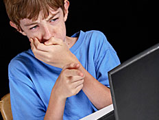 ילד בכחול יושב מול מחשב ומכסה את פיו (צילום: biffspandex, Istock)