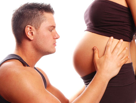 בחור שרירי בשחור מחזיק בטן של בחורה בהריון (צילום: istockphoto)