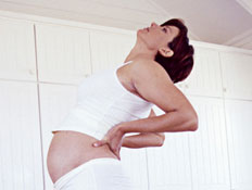 אישה בהריון מתמתחת אחורה בחדר מעוצב בלבן (צילום: jupiter images)