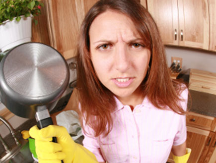 אישה זעופה במטבח בכפפות צהובות מחזיקה סיר מעליה (צילום: istockphoto)