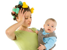 בחורה מתוסכלת בירוק עם רולים מחזיקה תינוק ותופסת את הראש (צילום: Tomasz Trojanowski, Istock)