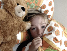 ילד בלונדיני במיטה עם דובי לידו מתחבא מתחת לשמיכה (צילום: istockphoto)
