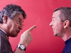 שני גברים משוחחים על רקע ורוד אחד במשקפיים מפנה אצבע לשני
