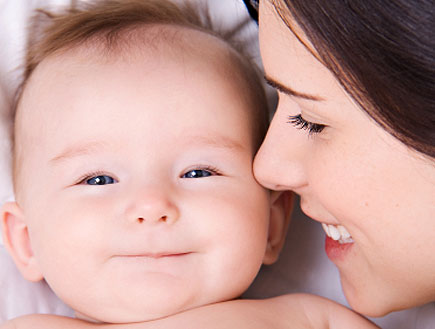 קלוז אפ של אישה מצמידה פניה לתינוק מחייך (צילום: snapphoto, Istock)