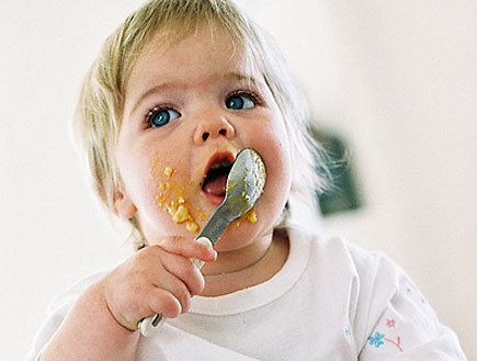 תינוקת אוכלת ומרוחה במחית ויושבת על הצלחת (צילום: jupiter images)