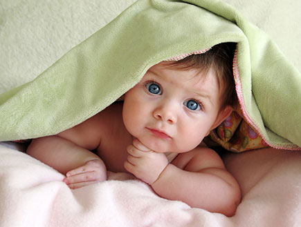 תינוק יפה וערום מציץ מתחת לשמיכה ירוקה על מיטה (צילום: ekinsdesigns, Istock)