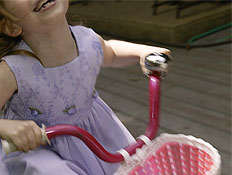 ילדה שמחה בשמלה סגולה על אופניים ורודות עם סל (צילום: jupiter images)