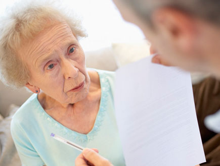 איש מחזיק נייר ועט מול אישה מבוגרת בתכלת (צילום: jupiter images)