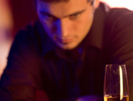 בחור בחום יושב ומביט בכוס משקה וטבעת שעל הבר (צילום: g_studio, Istock)