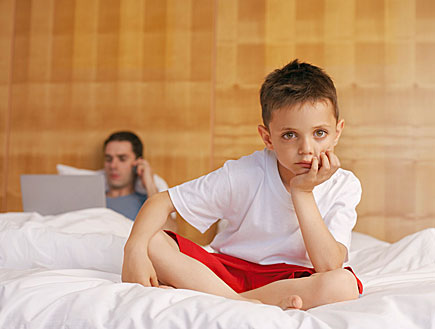 ילד יושב על מיטה ואביו ברקע (צילום: jupiter images)