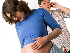 אישה בהריון בכחול ומאחוריה גבר מדבר בסלולרי (צילום: istockphoto)