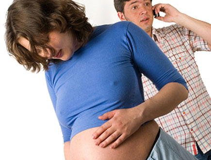 אישה בהריון בכחול ומאחוריה גבר מדבר בסלולרי (צילום: istockphoto)