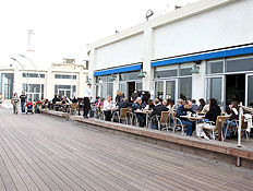 אנשים יושבים בחזית בית קפה בנמל תל אביב (צילום: עודד קרני)