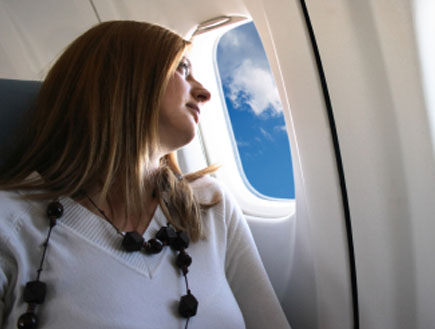 אישה במטוס, יושבת בכסא ליד החלון (צילום: tulcarion, Istock)