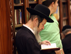 איש דתי חרדי קורא בספר מאחוריו איש בירוק (צילום: מערכת MAKO 5)