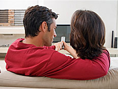 זוג מחזיק שלט מול טלוויזיה (צילום: jupiter images)