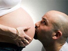 גבר קירח מנשק בטן של אישה בהריון מחייכת בלבן (צילום: MathieuViennet, Istock)