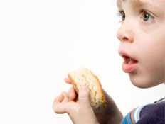 פרופיל של ילד קטן בפה פתוח מחזיק לחם (צילום: Leslie Banks, Istock)