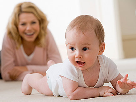 תינוק בלבן זוחל ומאחוריו אימו מחייכת בורוד (צילום: jupiter images)