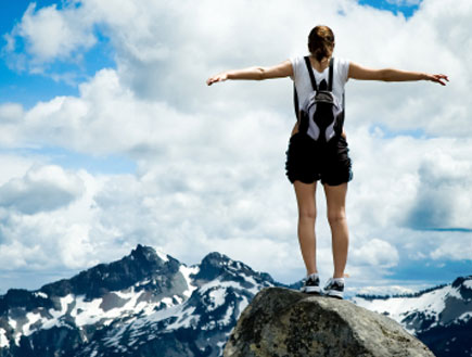 חופש - אישה עומדת על פסגת הר ופורשת ידיים לצדדים (צילום: iStock)