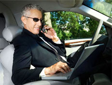 איש עסקים עם מחשב נייד מדבר בנייד במכונית