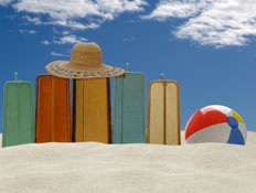 חופשת קיץ - מזוודות, כדור וכובע על חוף הים (צילום: iStock)