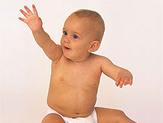 תינוק ערום יושב על הרצפה ומרים את היד (צילום: jupiter images)