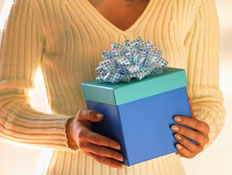 גוף אישה בסריג לבן מחזיקה קופסת מתנה כחולה עטופה ב