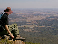 אדם יושב על סלע, מביט לעבר נוף של הרים וירוק (צילום: אור גץ)