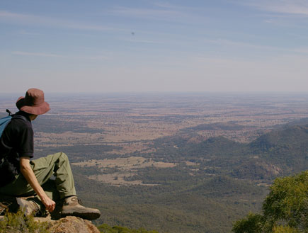 אדם יושב על סלע, מביט לעבר נוף של הרים וירוק (צילום: אור גץ)
