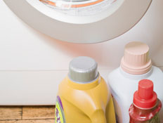 בקבוקי נוזל לכביסה ליד פתח של מכונת כביסה לבנה (צילום: jupiter images)