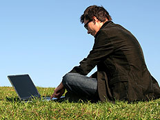 אדם יושב על דשא עם לפטופ (צילום: אור גץ, ShutterStock)