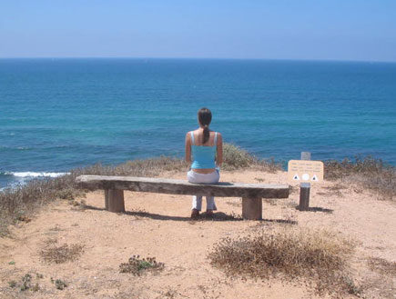 בחורה יושבת על ספסל מול הים באפולוניה