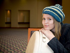 גברת צעירה מחכה עם מזוודה בלובי של מלון (צילום: iStock)